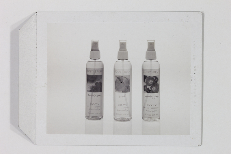 Fotografía publicitaria de estudio que muestra tres envases de atomizador 'Body Fresh' de la marca Coty, alineados verticalmente. Las fragancias identificadas son Turquoise Seas, Peach y Morning Glory. Cada botella presenta etiquetas con texto bilingüe en inglés y español, destacando el eslogan 'llévame contigo'. Se trata de una toma de producto en blanco y negro con iluminación controlada.