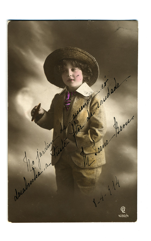 Retrato de estudio de una persona joven con indumentaria formal masculina de inicios del siglo XX, compuesta por un traje de saco y pantalón en lana texturizada, cuello rígido y sombrero de ala circular. La imagen está intervenida con inscripciones manuscritas en portugués que expresan sentimientos de ausencia y nostalgia, fechadas en abril de 1914.
