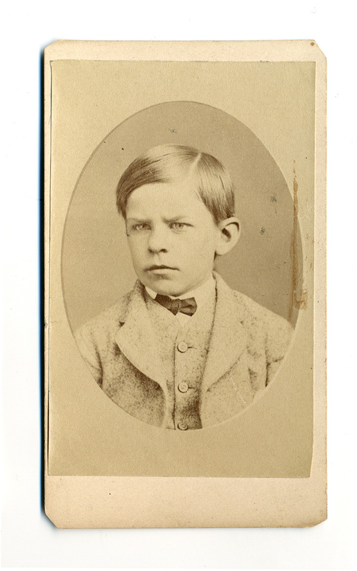 Retrato de estudio de un niño con gesto serio, capturado en un encuadre de viñeta ovalada. El menor viste un saco formal de textura gruesa, probablemente lana, con tres botones visibles, acompañado de una camisa de cuello rígido y un pequeño lazo o moño oscuro, reflejando las convenciones sociales del retrato infantil decimonónico.