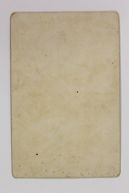 Esta imagen documenta el reverso de un soporte fotográfico histórico, posiblemente una tarjeta de gabinete o postal antigua. No contiene información visual, manuscrita ni sellos de fotógrafo, mostrando únicamente el desgaste natural del papel, el cual presenta una pátina amarillenta y manchas de oxidación ácida (foxing) consistentes con materiales de finales del siglo XIX.