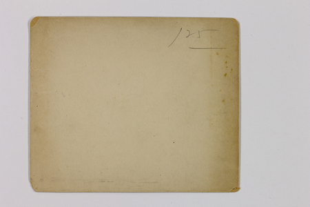Vista posterior de una fotografía histórica sobre soporte de papel. Presenta un tono amarillento debido a la oxidación de la celulosa y el paso del tiempo, con presencia de manchas de oxidación o humedad tipo foxing. Se observa una marca manuscrita a lápiz en el cuadrante superior derecho con la cifra '125', indicativa de una clasificación de inventario o control archivístico.