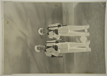 Retrato de estudio o exterior de dos niños de diferentes edades durante una ceremonia de Primera Comunión. Ambos visten trajes formales claros con brazaletes distintivos en el brazo derecho; sostienen rosarios y velas largas ceremoniales. La composición centrada y la vestimenta reflejan las prácticas sociales y religiosas católicas predominantes en el México de mediados del siglo XX.