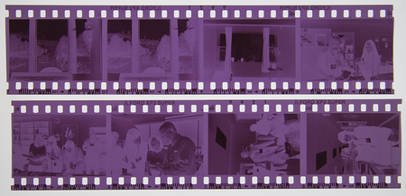 Dos tiras de película negativa de 35mm con escenas de interiores que documentan la vida cotidiana contemporánea. Se observa a una persona trabajando frente a una computadora portátil, así como diversas tomas de un establecimiento público, posiblemente una cafetería o restaurante, donde personas interactúan en un entorno social urbano de finales del siglo XX o inicios del XXI.